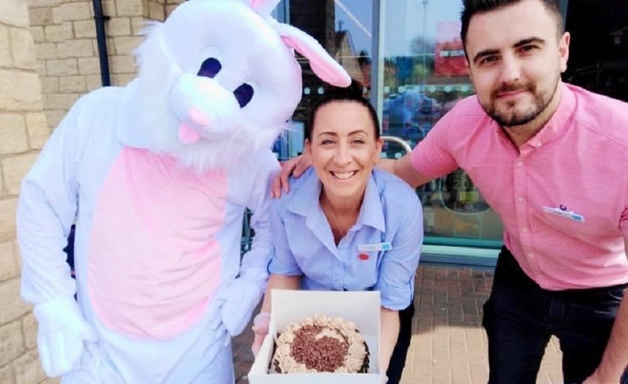 Two people holding a cake and a person dressed as bunny