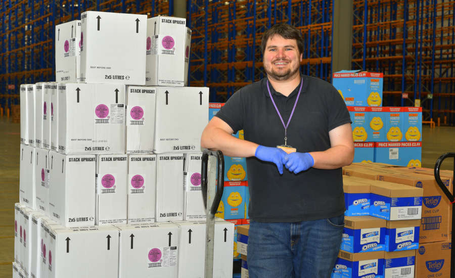 Volunteer standing next to pallets of food and drinks